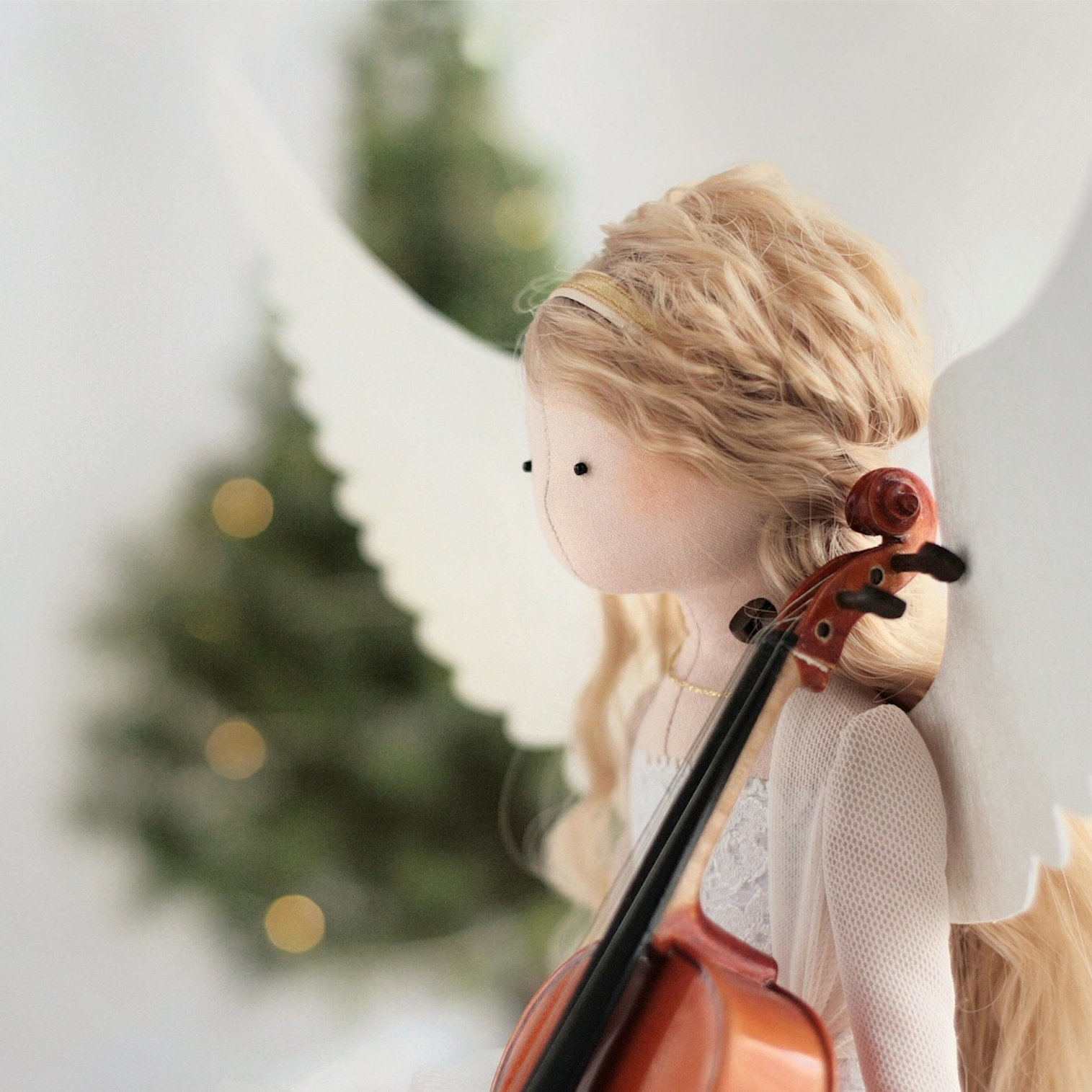 Anioł gra na skrzypcach na tle choinki